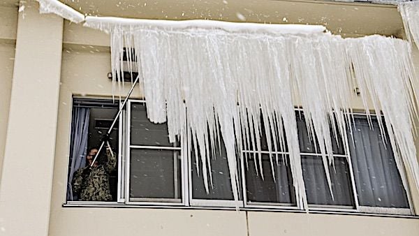 Navy Petty Officer 2nd Class Jason Noel knocks down ice dams from a building at Naval Air Facility Misawa, Japan, Dec. 16, 2020. (U.S. Navy photo by Seaman Benjamin Ringers)