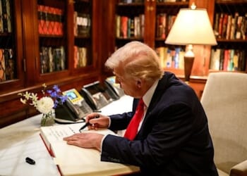 President Donald Trump signs the guest book at the ambassador's residence in Tokyo, Japan on Tuesday, Oct. 28, 2025, as Secretary of Commerce Howard Lutnick, Ambassador George Glass, and his wife, Mary Glass, look on. (Official White House photo by Molly Riley)