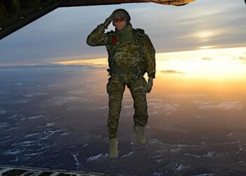 A U.S. soldier assigned to 1st Battalion, 10th Special Forces Group (Airborne) salutes his fellow soldiers while jumping out of a C-130 Hercules aircraft over a drop zone in Germany, Feb. 24, 2015. (U.S. Army photo by Visual Information Specialist Jason Johnston)