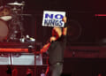 Bruce Springsteen, in concert, holding up a "No Kings" sign.