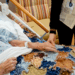 A hospice patient is in bed with her hand being held by a hospice caregiver.