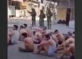 Hamas prisoners sat on the street, stripped to their underwear, as they waited to be loaded onto truck