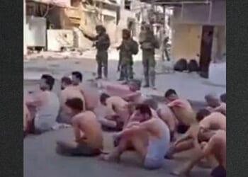 Hamas prisoners sat on the street, stripped to their underwear, as they waited to be loaded onto truck