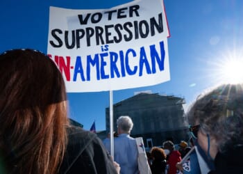 Protestors with a sign that says "Voter suppression is un-American"