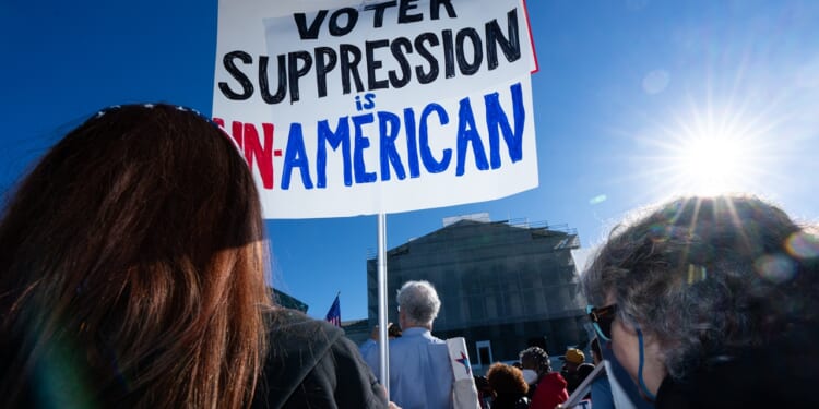 Protestors with a sign that says "Voter suppression is un-American"