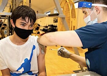 A Yokosuka Middle School student, receives the Pfizer COVID-19 vaccine from Hospitalman Alec Bowen, assigned to U.S. Naval Hospital Yokosuka, during a vaccine distribution at Commander, Fleet Activities Yokosuka
