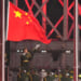 Chinese soldier points to large Chinese flag as row of Chinese soldiers salute.