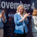 Abigail Spanberger, flanked by Jay Jones and Ghazala Hashmi clap in front of bus during campaign rally.
