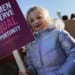 A young girl protests with a sign that says "Women deserve equal opportunity. Save women's sports."