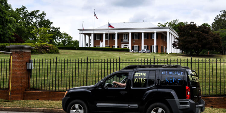 A demonstrator drives past the Governor's Mansion during a drive by protest in Atlanta, Georgia.