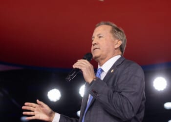 Texas Attorney General Ken Paxton speaking into a microphone
