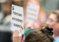 A person holds a sign reading, "Protect trans and nonbinary students!"