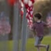 A boy runs among U.S. flags in a field