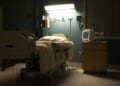 A bed in a darkened, empty hospital room.