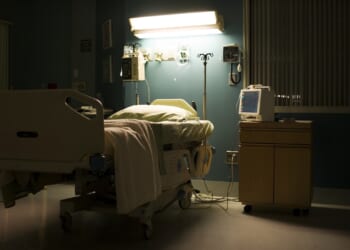 A bed in a darkened, empty hospital room.