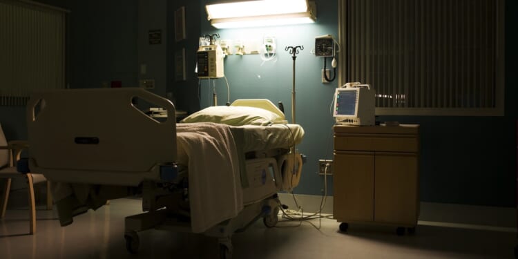 A bed in a darkened, empty hospital room.