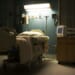 A bed in a darkened, empty hospital room.