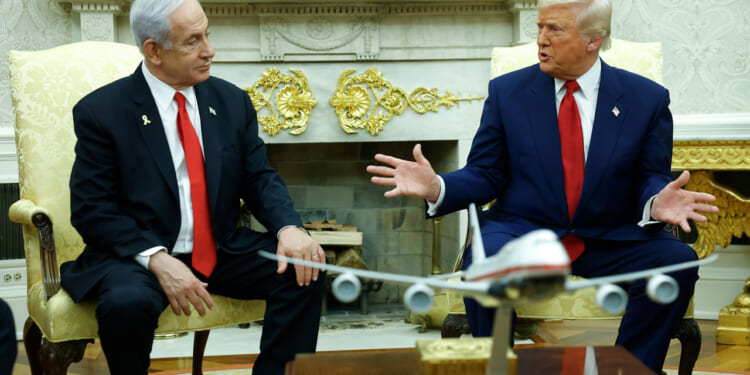 Donald Trump gestures to Benjamin Netanyahu as they sit in the Oval Office.