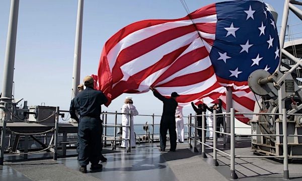 Sailors hoist the battle ensign aboard the amphibious assault ship USS Tripoli, May 2, 2022, as the ship departs Naval Base San Diego. (U.S. Navy photo by Mass Communication Specialist Seaman Austyn Riley)