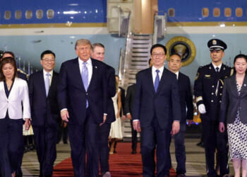 U.S. President Donald Trump walks to his motorcade as he is greeted by Chinese officials at Beijing Capital International Airport.