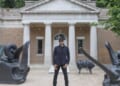 A man standing between two statues