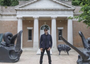A man standing between two statues