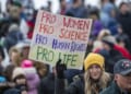 A protester holds a sign that says "Pro women pro science pro human rights pro life"