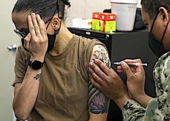 Hospital Corpsman 3rd Class Kyle Massey, assigned to the submarine tender USS Emory S. Land, administers the first dose of the Moderna COVID-19 vaccine to Machinist Mate 3rd Class Brandy Mingus, also assigned to Emory S. Land, at Mare Island Dry Dock, in Vallejo, California, March 18, 2021. (U.S. Navy photo by Mass Communication Specialist 3rd Class Zachary Grooman)