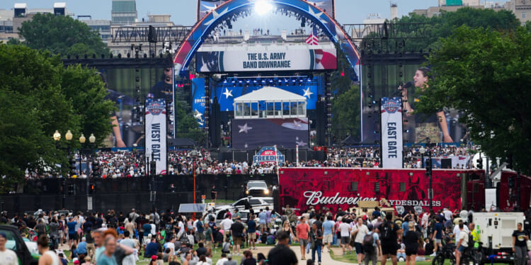 Crowd gathered for Freedom 250 event, with red, white and blue stage in the background.