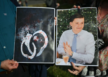 People hold images of victim Henry Nowak, and blood-covered handcuffs as they take part in a protest outside of Southampton Central Police Station in Southampton, southern England, on June 2, 2026, following the murder of Henry Nowak by Vickrum Digwa. Body camera footage of a dying student who was handcuffed by British police after being stabbed by a Sikh man and falsely accused of racially abusing his murderer sparked outrage Tuesday. (Photo by JUSTIN TALLIS / AFP via Getty Images)