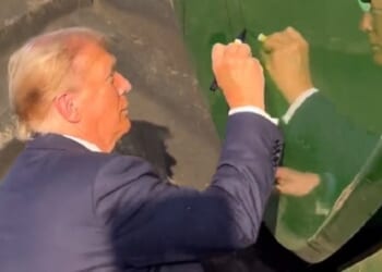 Former President Donald Trump autographs a farming combine Sunday in Iowa.