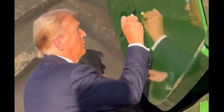 Former President Donald Trump autographs a farming combine Sunday in Iowa.