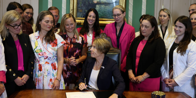 Massachusetts Governor Maura Healey turns to the women gathered behind her after signing a bill prioritizing patient access to care to strengthen abortion protections in Massachusetts at the State House on August 10, 2026. (Photo by Jessica Rinaldi/The Boston Globe via Getty Images)
