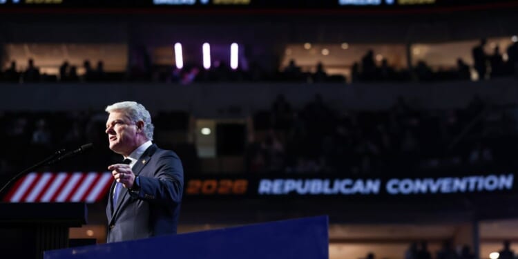 Rep. Mike Collins is pictured in a suit and speaks at a podium during the Republican National Convention, with REPUBLICAN CONVENTION and 2028 visible on a screen in the background, and an audience in a darkened arena.