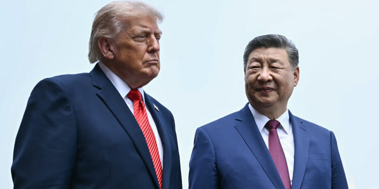 Donald Trump and Xi Jinping in dark suits and red ties stand side by side outdoors. One looks serious, facing forward, while the other smiles gently, looking at his companion. Both have short, neatly styled hair and stand against a pale sky background.