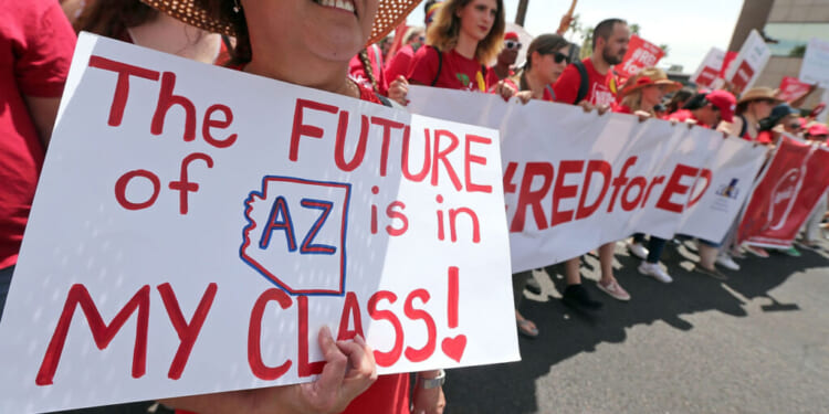 A person holds a sign that says The FUTURE of AZ is in MY CLASS! during a Red for Ed protest.