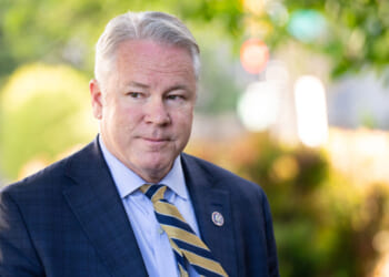 Middle-aged man in a suit and tie with a congressional lapel pin.