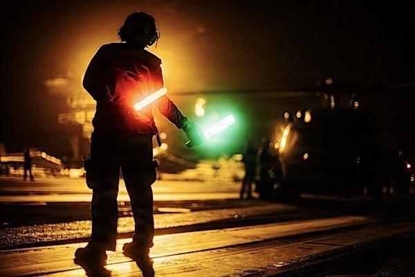 A sailor signals to a Navy MH-60R Sea Hawk helicopter on the flight deck aboard the aircraft carrier USS George Washington in the U.S. 5th Fleet area of operations, Sept. 18, 2026. (U.S. Navy photo)